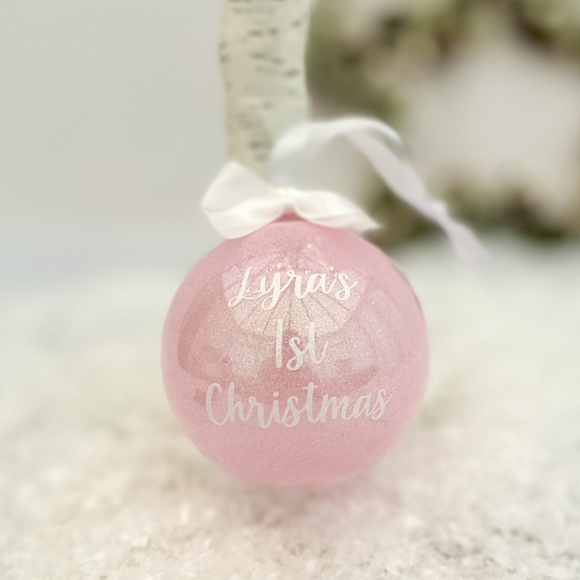 baby pink glitter bauble with the wording Lyra's 1st Christmas