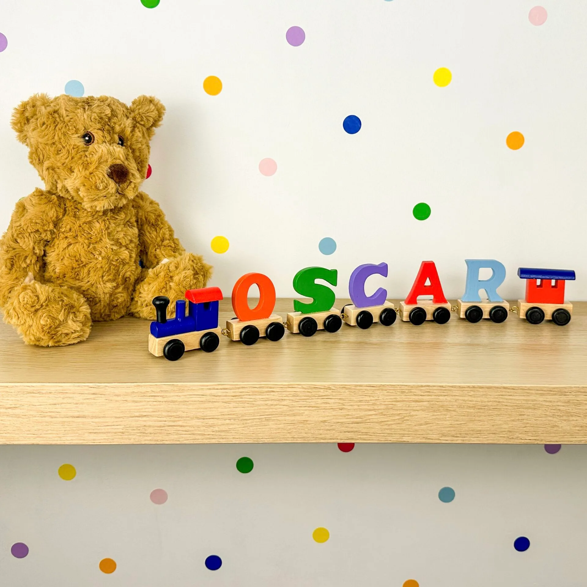 red and blue engine pulling multi coloured train letters spelling out name Oscar